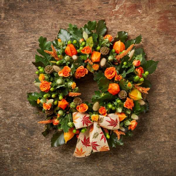 Finished Halloween flower wreath with orange, green and brown accents and an autumnal ribbon