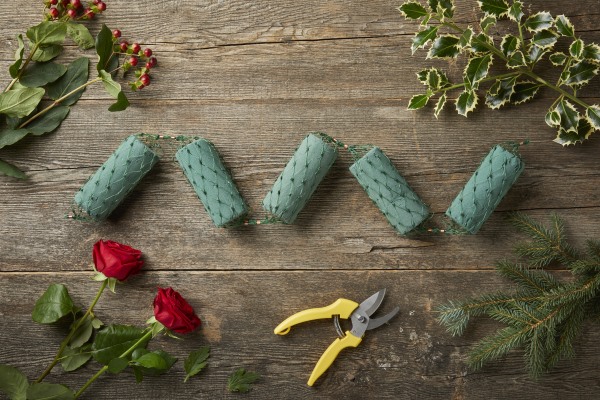 OASIS® Ideal Floral Foam Netted Garland on a wooden table next to festive foliage.  